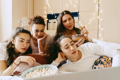 Multiracial female friends watching movie together on laptop at home