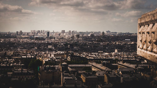 High angle view of city buildings against cloudy sky