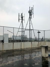 Electricity pylon by building against sky