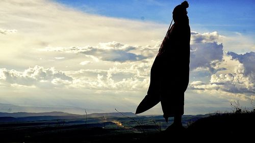 Silhouette person standing on field against sky during sunset