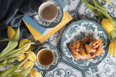 Flat lay food, sweet puff, tea in a vintage porcelain cup and a stack of books