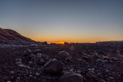 Scenic view of rocks against clear sky during sunset