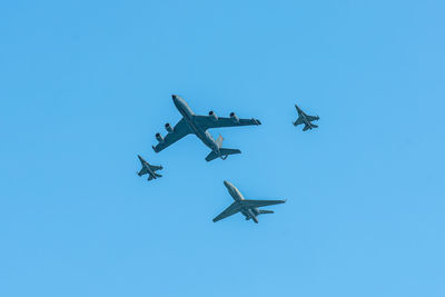 Low angle view of airplane flying against clear blue sky