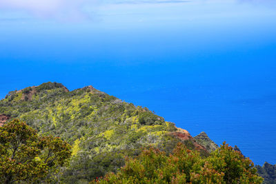 Scenic view of sea and mountains against blue sky