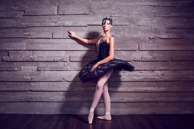 Ballet dancer dancing against wall