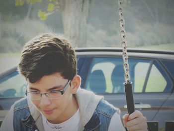 Close-up of boy sitting on swing