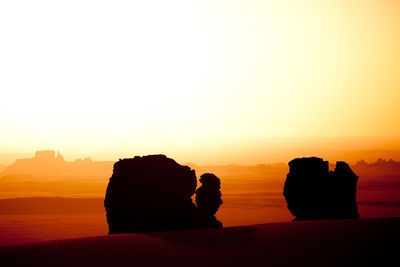 Silhouette rocks on rock against sky during sunset