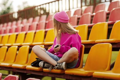 A blonde girl is sitting cross-legged at the school stadium