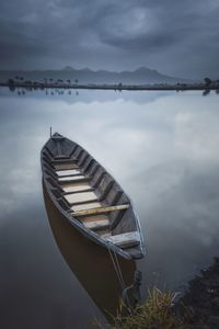 Boat moored in water against sky