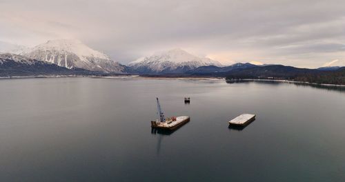 Scenic view of lake by snowcapped mountains against sky