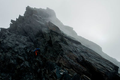 Man on rock formation against sky