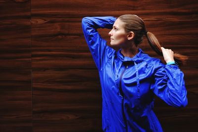 Young woman looking away while standing against purple wall