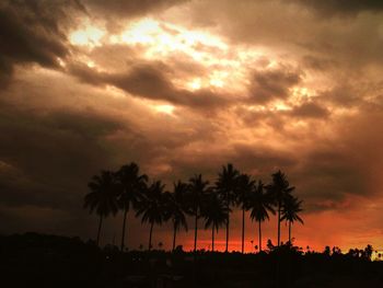 Silhouette of trees against cloudy sky