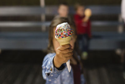 Girl showing vanilla ice cream with sprinkles
