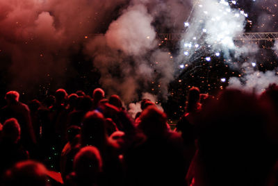 Silhouette crowd by fireworks during music concert at night