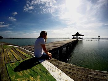 Woman on pier over sea against sky