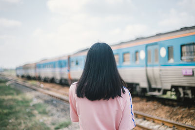 Rear view of woman standing on train at railroad station