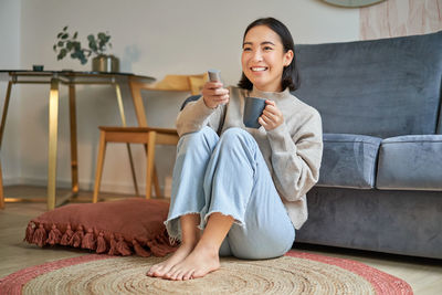 Young woman sitting on sofa at home