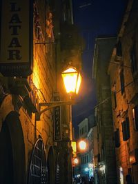 Low angle view of illuminated street light against building at night