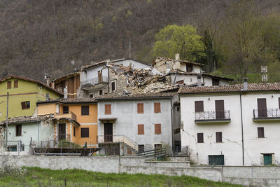 Houses on field by buildings in city