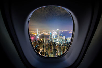 Illuminated cityscape against sky seen through glass window