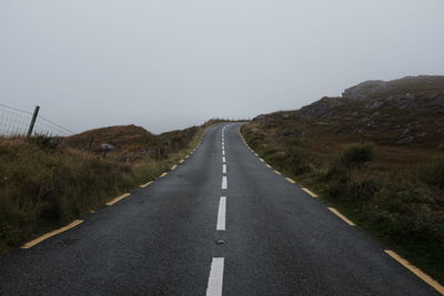 Empty road amidst landscape against clear sky