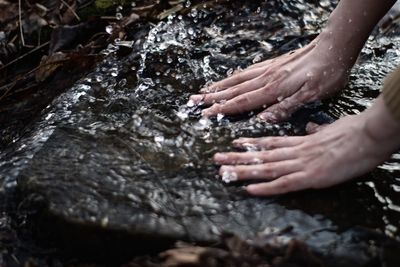 Cropped image of woman washing hands in river