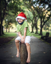 Full length portrait of smiling boy sitting on bollard