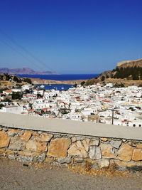 Scenic view of town by sea against clear blue sky