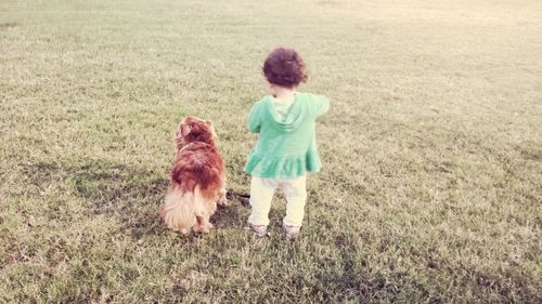 Rear view of toddler and dog outdoors