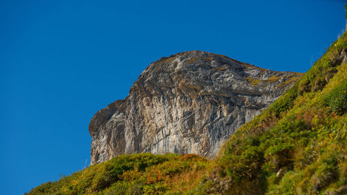 Low angle view of rock formation against clear blue sky