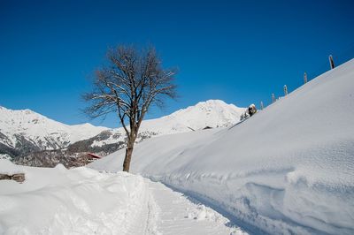 Scenic view of snow covered mountains against clear blue sky