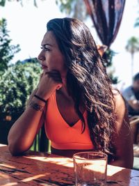 Young woman looking away while sitting on table