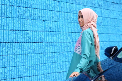 Woman standing by blue wall