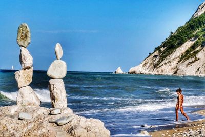 People on rocks at beach against sky