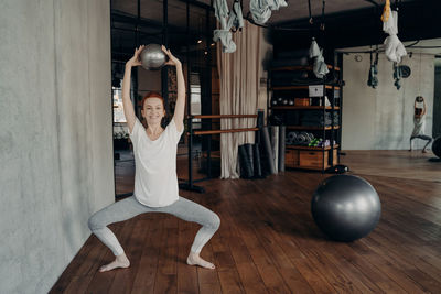 Full length of woman with arms raised on floor