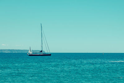 Sailboat sailing on sea against clear sky