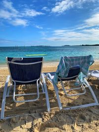 Chairs on beach against sky