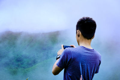 Rear view of man photographing mountain