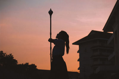 Silhouette woman standing against orange sky