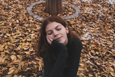 Woman with eyes closed sitting on land during autumn
