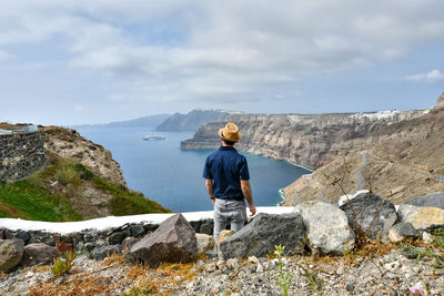 Rear view of man standing on rocks against sky