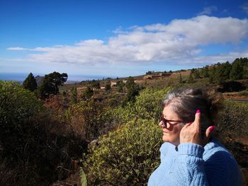 Portrait of woman standing by plants against sky