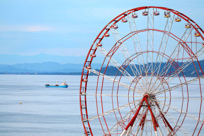 Ferris wheel by sea against sky