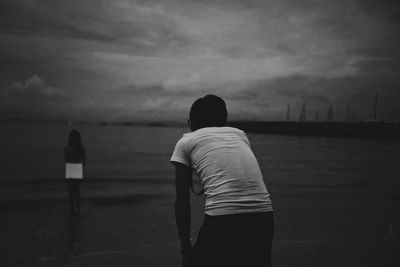 Rear view of man standing against cloudy sky