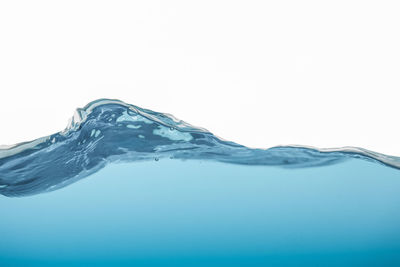 Close-up of water splashing over sea against clear sky