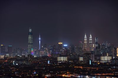 Illuminated buildings in city against sky at night