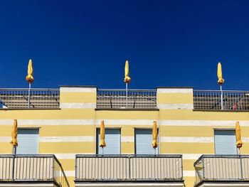 Low angle view of yellow buildings against clear blue sky