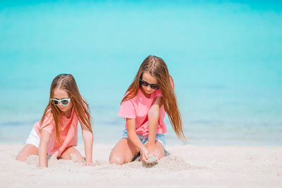 Sisters plying with sand on beach