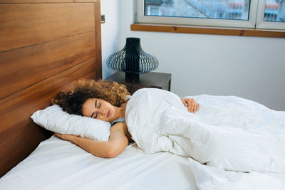 High angle view of young woman sleeping on bed at home